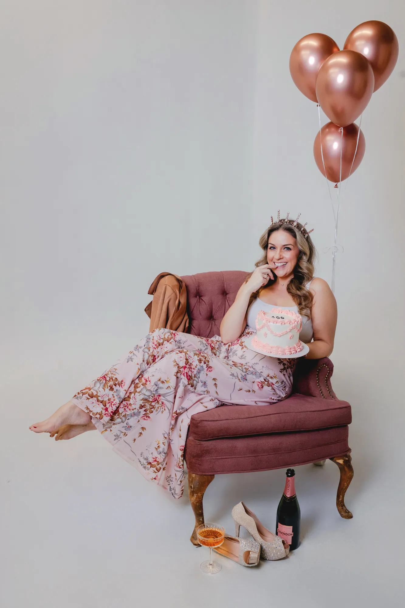 Jen Klaus in a tiara laughing with a pink 100 cake, celebrating 100 weddings planned